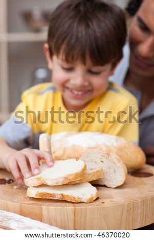Adorable little boy eating bread with his father in the kitchen