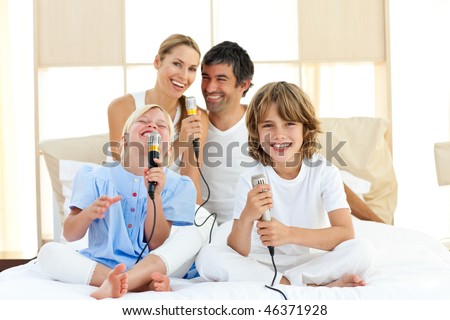 Active family singing together sitting on bed