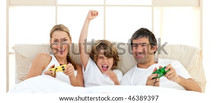 Smiling little boy playing video game with his family in the bedroom