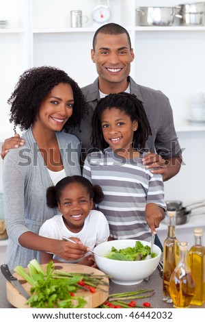 Ethnic family preparing salad together in the kitchen