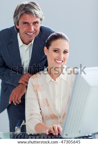 Mature manager helping his colleague work at a computer in the office