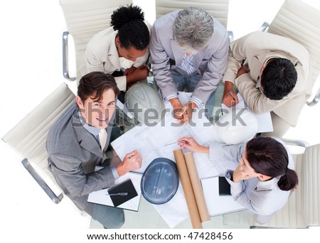 High angle of international architects studying blueprints in a meeting