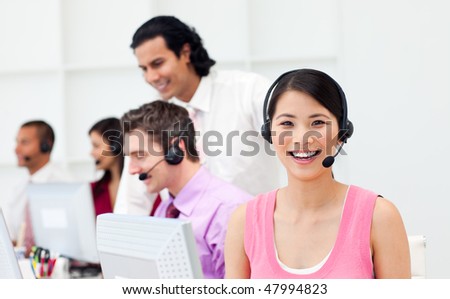 Portrait of an Asian customer agent and her team in a call center