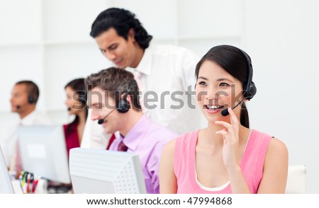Beautiful Asian customer agent and her team in a call center