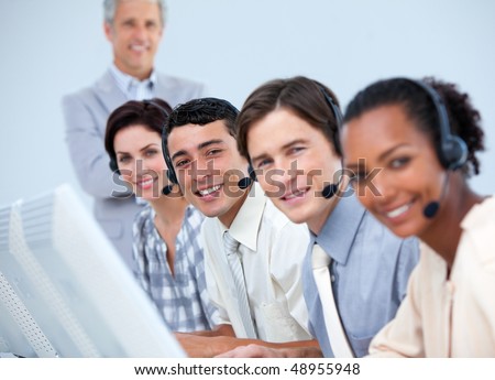 Cheerful business partners working with their manager in a call center