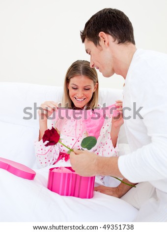Charming husband giving a present to his wife in the bedroom