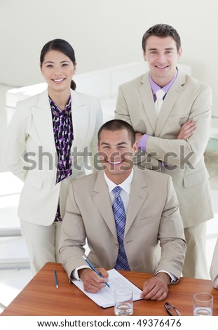 Young confident manager and his team smiling at the camera in the office