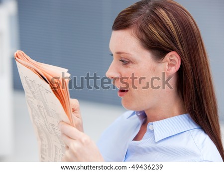 Surprised businesswoman reading newspaper in her office