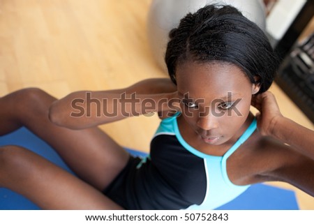 Serious ethnic woman in gym clothes working out at home