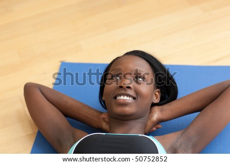 Smiling woman in gym clothes doing sit-ups at home