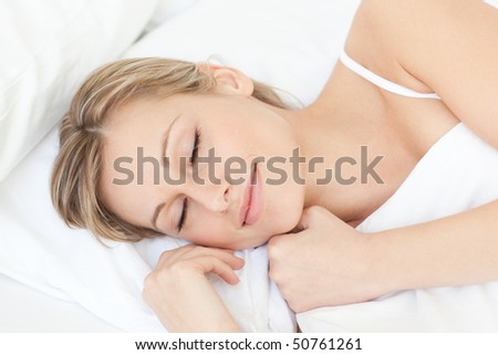 Bright tired woman sleeping on her bed at home