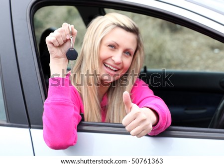Happy female driver showing a key with a thumb up after buying a new car