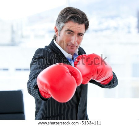 Furious businessman wearing boxing gloves in his office