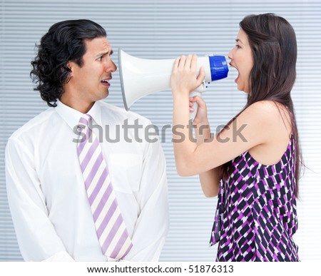 Furious businesswoman yelling through a megaphone at a colleague