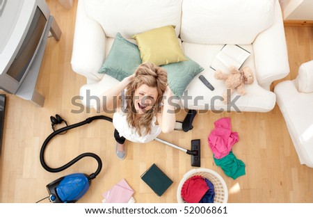 High angle of an irritate blond woman vacuuming the living-room