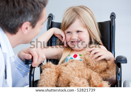 Laughing little girl sitting on the wheelchair at the hospital
