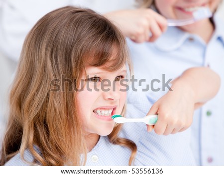 Happy girl brushing her teeth against a white background