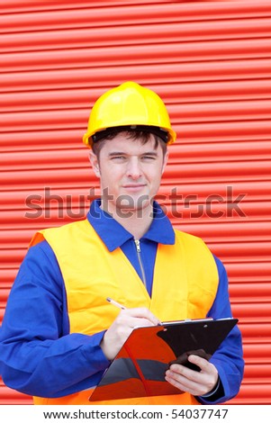 Happy male engineer writing his report at work