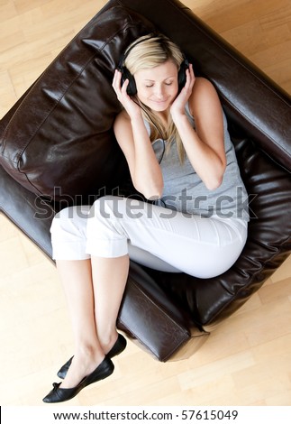 Relaxed woman listen to music with headphones sitting on a sofa