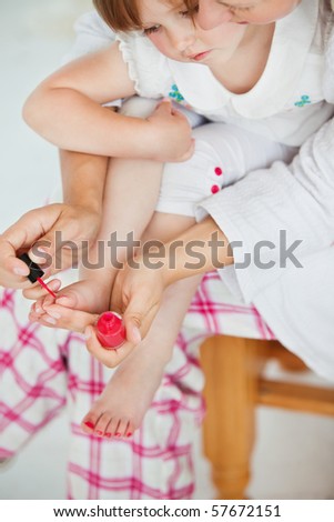 Mother making her daughter\'s nails in bathroom