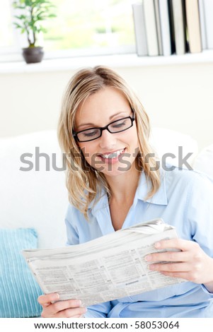 Attractive businesswoman reading the newspaper sitting on the sofa at home