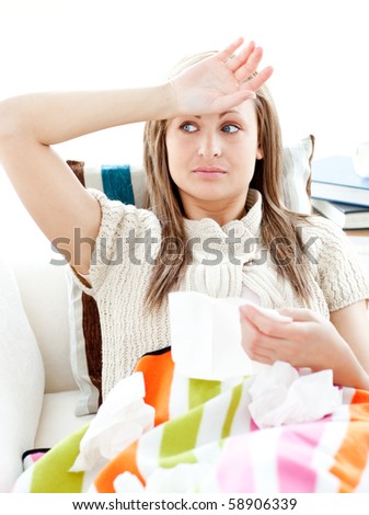 Sick young woman having fever lying on the sofa in the living room