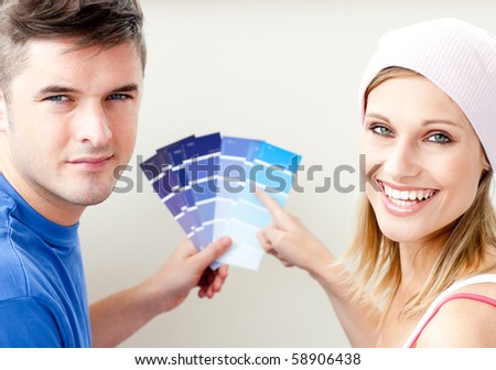 Cheerful couple with color samples for painting a room in their new home