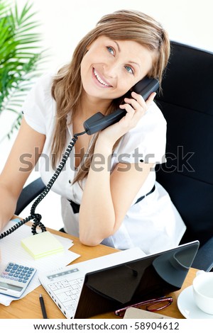 Self-assured businesswoman talking on phone sitting at her desk in the office
