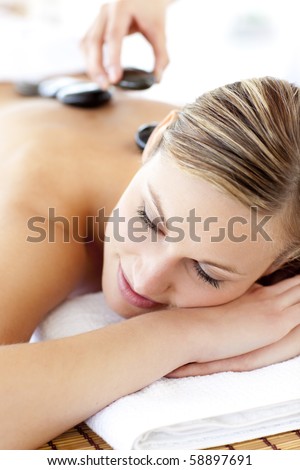 Charming young woman enjoying a back massage with hot stone in a spa center