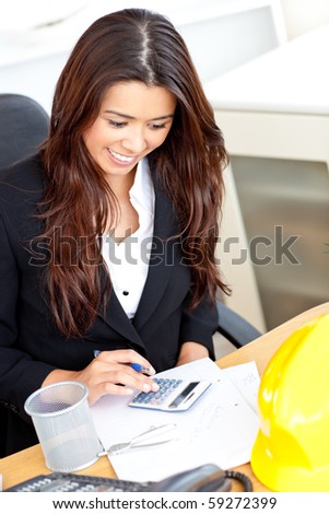 Ambitious businesswoman using her calculator in the office