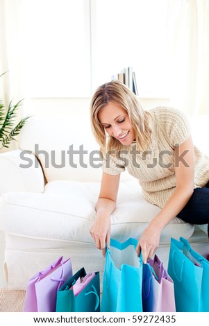 Happy woman at home after shopping looking into her shopping bags