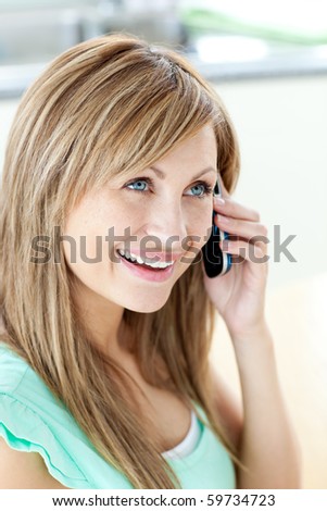 Cheerful woman answering the phone in the kitchen at home