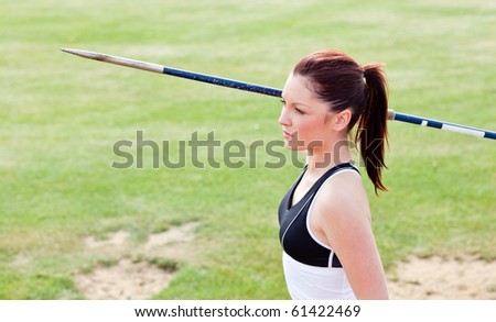 Concentrated female athlete ready to throw javelin in a stadium