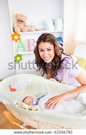 Attentive young mother taking care of her adorable baby at home