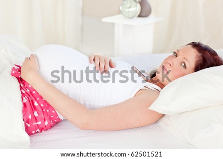 Caucasian pregnant woman resting n her bed in the bedroom at home