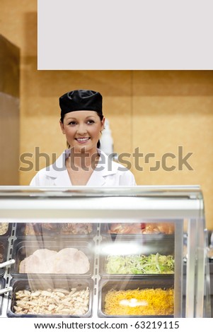 Portrait of a cute baker smiling at a customer in a  cafeteria