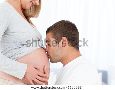 Lovely Future Dad Kissing The Belly Of His Wife Standing In The Bedroom ...