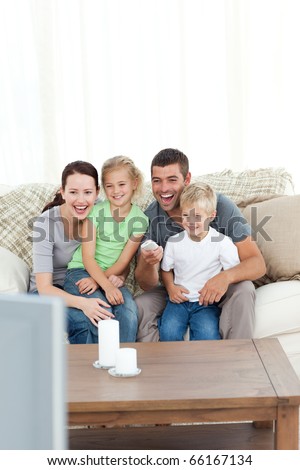 Happy family laughing while watching television sitting on the sofa at home