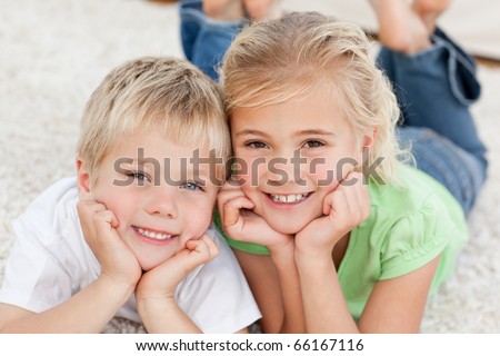 Portrait of siblings watching television on the floor in the living-room