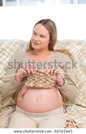 Future mother knitting and looking the side sitting in the living room