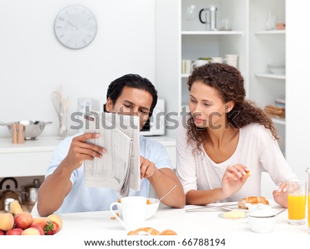 Happy couple reading the newspaper together during breakfast at home