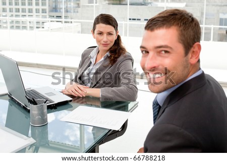 Happy businessman and businesswoman working together on a laptop during a meeting