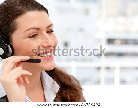 Smiling businesswoman talking on the phone with headphones on in an office
