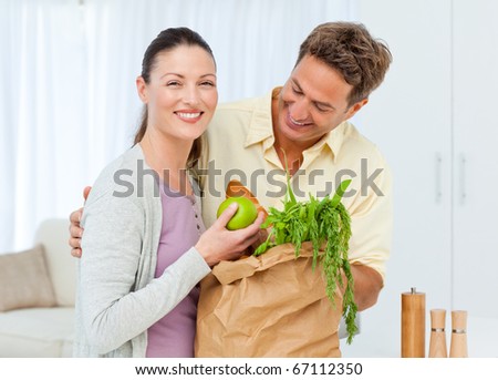 Happy couple coming back from the market with fruits , vegetables and bread in shopping bags