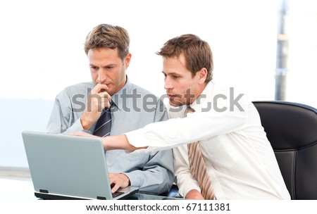 Two handsome businessmen working together on a project sitting at a table in the office