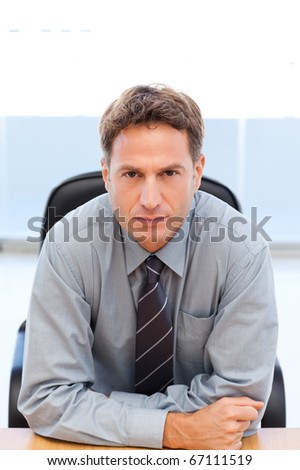 Serious manager sitting at a table in an office