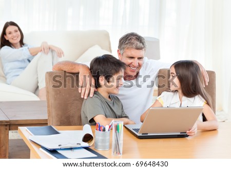 Children playing video games on the laptop while parents are looking about them