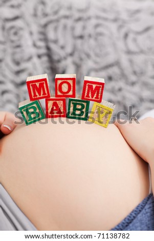 Pregnant young woman with cubes on her belly at home