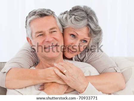 Mature woman hugging her husband at home