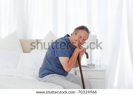 Retired man with his walking stick on his bed